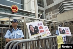 FILE - A policeman stands guard next to portraits of Chinese journalist Gao Yu during a demonstration calling for Gao's release from a prison in China, outside the Chinese liaison office in Hong Kong, April 17, 2015.