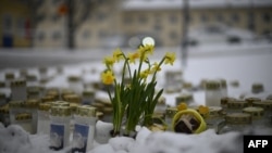 Candles and flowers are placed in the snow in front of the Viertola School to pay tribute to victims in Vantaa, in the north of the Finnish capital, Helsinki, on April 3, 2024. The day before, a 12-year-old allegedly opened fire inside the school, killing a classmate.