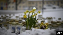 Lilin dan bunga diletakkan di atas salju di depan Sekolah Viertola untuk penghormatan kepada para korban di Vantaa, di utara ibu kota Finlandia, Helsinki, 3 April 2024. (Olivier MORIN / AFP)