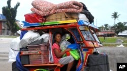 Typhoon survivors, some of whom are still living in tents, evacuate to safer grounds with their belongings at Tanauan township, Leyte province in central Philippines Thursday, Dec. 4, 2014, in anticipation of the incoming Typhoon Hagupit which is forecast