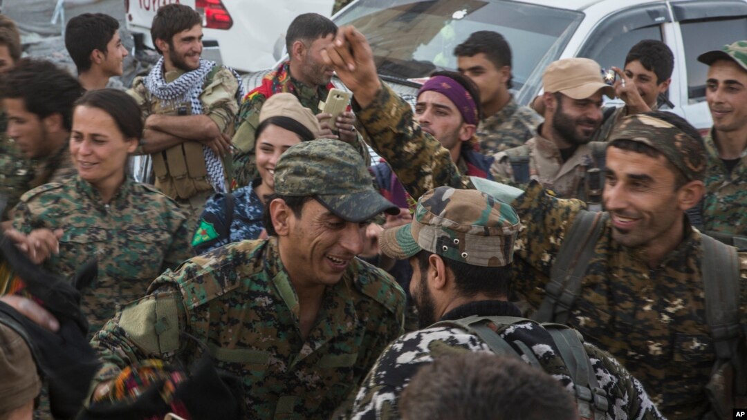 Miembros de las Fuerzas Democráticas Sirias, que respalda Estados Unidos, bailan la tradicional danza siria "dabka" mientras celebran la liberación de Raqqa frente al estadio que fue el último bastión de ISIS en la ciudad. Oct. 20, 2017.