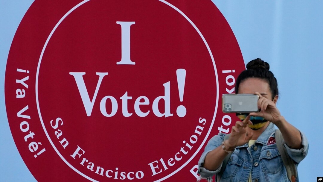 Una mujer toma una foto frente a un letrero donde se lee: "Yo voté", en un centro de votación en San Francisco, el lunes 2 de noviembre de 2020. [Foto: AP]