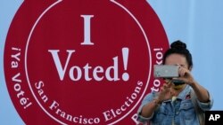 Una mujer toma una foto frente a un letrero donde se lee: "Yo voté", en un centro de votación en San Francisco, el lunes 2 de noviembre de 2020. [Foto: AP]