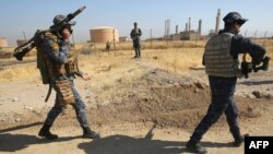 Iraqi forces walk past an oil production plant as they head towards the city of Kirkuk during an operation against Kurdish fighters on Oct. 16, 2017. 