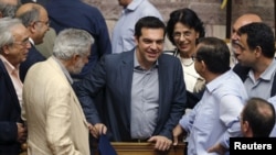 အေသင်မြို့တော်ရှိ လွှတ်တော်တွင် မဲခွဲဆုံးဖြတ်ပွဲတခုအပြီး တွေ့ရသည့် ဂရိဝန်ကြီးချုပ် Alexis Tsipras (လယ်)။ ဇူလိုင် ၁၁၊ ၂၀၁၅။