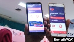 Dua relawan menunjukkan aplikasi Wonder yang ada dalam perangkat telepon mereka. (Foto:VOA/ Nurhadi)