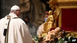 Pope Francis stands in front of a statue of Baby Jesus as he celebrates Mass on Christmas Eve at St. Peter's basilica at the Vatican Dec. 24, 2020. 