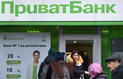 FILE - A client walks out as others arrive at the office of the PrivatBank in the center of Kyiv, Dec. 19, 2016.