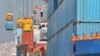 Workers look at cranes lifting containers onto cargo vessels at a port in Yantai, Shandong province, China October 17, 2019. 