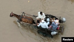 Keluarga Pakistan naik gerobak yang ditarik kuda untuk mengarungi banjir di Lahore (4/9).