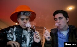 FILE - Customers puff on e-cigarettes at the Henley Vaporium in New York City, Dec. 18, 2013.