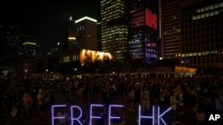 People wearing masks depicting Jimmy Sham hold a banner during an anti-government protest in Hong Kong, Oct. 18, 2019.