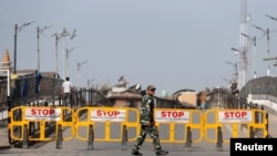 FILE - An Indian security force personnel member walks past barricades during restrictions imposed by authorities following the death of Syed Ali Shah Geelani, a Kashmiri veteran separatist politician, in Srinagar, September 3, 2021. 