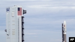 A United Launch Alliance Atlas V rocket that will launch to Mars leaves the vertical integration facility, left, as it rolls out to Space Launch Complex 41 at the Cape Canaveral Air Force Station, Tuesday, July 28, 2020, in Cape Canaveral, Fla. The…