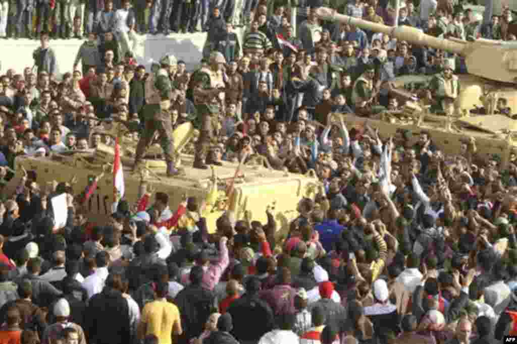 Armed soldiers look down on protestors surrounding military vehicles in Tahrir Square in Cairo, Egypt, Wednesday, Feb.2, 2011. Several thousand supporters of President Hosni Mubarak, including some riding horses and camels and wielding whips, clashed with
