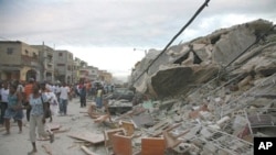 Haitians walk past damaged buildings in Port-au-Prince, 12 Jan 2010