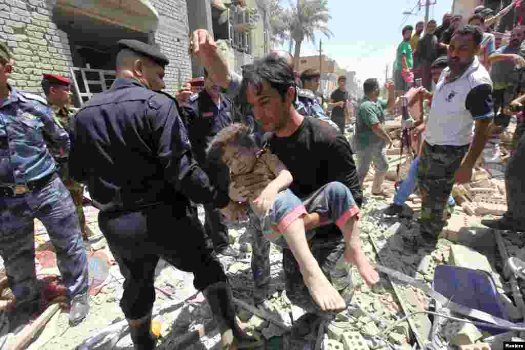 A man carries an injured child found in the rubble after an Iraqi Sukhoi jet accidentally dropped a bomb in Ni'iriya district in Baghdad, Iraq, killing at least five people and destroying several houses. 