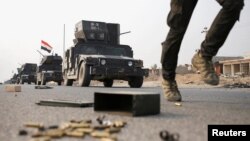 An Iraqi special forces soldier runs as other drive in armored vehicles on a road near Mosul, Iraq, Oct. 25. 2016.