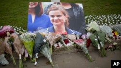 An image and floral tributes for Jo Cox, the 41-year-old British Member of Parliament shot to death yesterday in northern England, lie placed on Parliament Square outside the House of Parliament in London, June 17, 2016. 