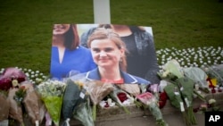 An image and floral tributes for Jo Cox, the 41-year-old British Member of Parliament shot to death yesterday in northern England, lie placed on Parliament Square outside the House of Parliament in London, June 17, 2016. 