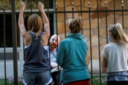 FILE - Family and friends visit a man while staying outside Bethany Retirement Living, as they practice social distancing amid the spread of the coronavirus disease, in Fargo, North Dakota, July 15, 2020.