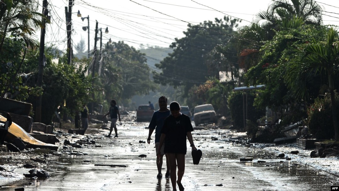 Personas caminan por una calle de Planeta, municipio de La Lima, en el departamento hondureño de Cortés, el 9 de noviembre de 2020, luego del paso del huracán Eta, ahora degradado a tormenta tropical.