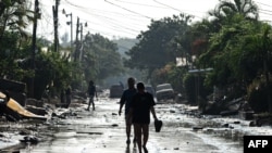 Personas caminan por una calle de Planeta, municipio de La Lima, en el departamento hondureño de Cortés, el 9 de noviembre de 2020, luego del paso del huracán Eta, ahora degradado a tormenta tropical.