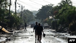 La gente camina por una calle de Planeta, municipio de La Lima, en el departamento hondureño de Cortés, el 9 de noviembre de 2020, luego del paso del huracán Eta.