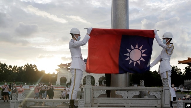 FILE - Two soldiers fold the national flag during the daily flag ceremony in Liberty Square of Chiang Kai-shek Memorial Hall in Taipei, Taiwan, on July 30, 2022.