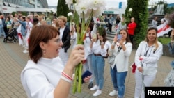 FILE - Olga Kovalkova, representative of the Coordination Council for members of the Belarusian opposition, holds flowers as she attends an opposition demonstration to protest presidential election results in Minsk, Belarus, Aug. 22, 2020.