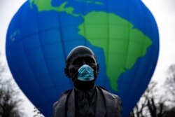 FILE - The bust of French statesman Robert Schuman, one of the founders of the European Union, is seen while environmental activists launch a hot air balloon during a demonstration outside an EU summit in Brussels, Dec. 10, 2020.