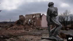 Spomenik iz vremena Sovjetskog saveza, posvećen vojnicima iz Drugog svjetskog rata, ispred uništene kuće u blizini Avdejevke u Ukrajini, 21. marta 2024. (Foto: AP/Alex Babenko)