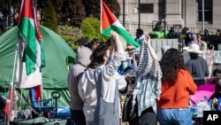 Dos estudiantes conversan en un campamento donde protestan a favor de los palestinos, el lunes 22 de abril de 2024, en la Universidad de Columbia, en Nueva York. 