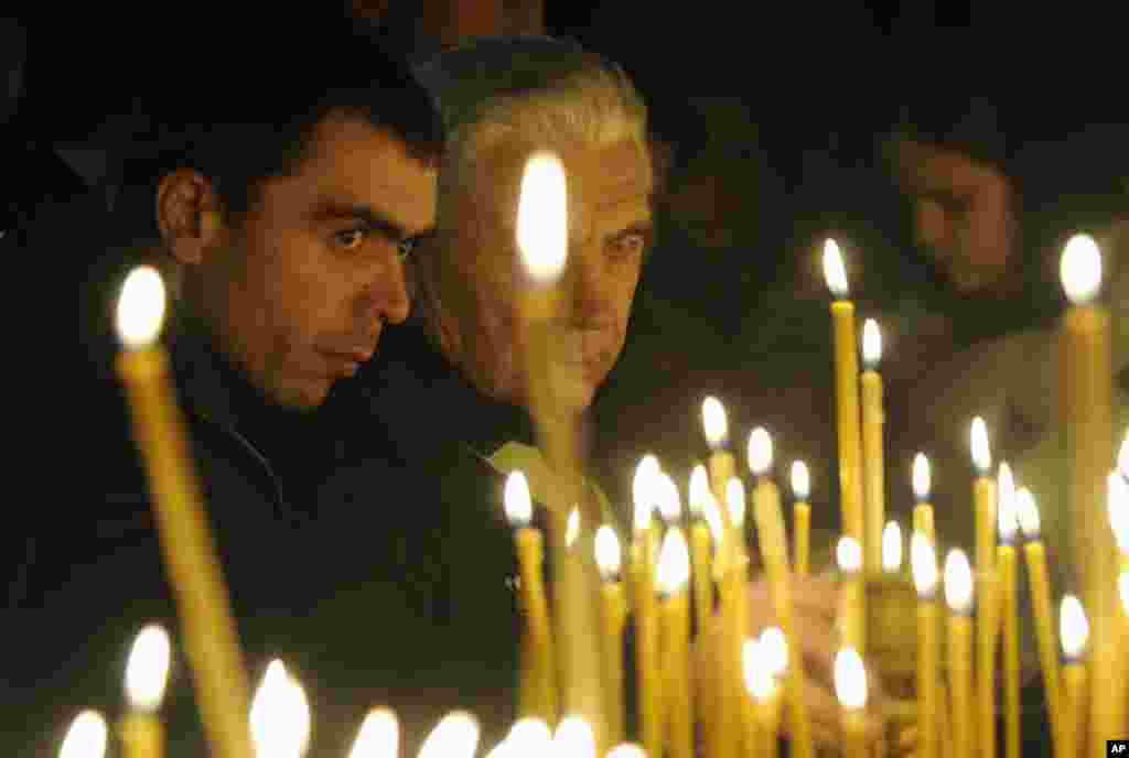 People light candles in a church to mark the Orthodox Christmas in the Kyiv-Pechersk Lavra church in Kiev, Ukraine, Friday, Jan. 6, 2012.  (AP)