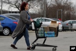 A shopper wheels her cart full of groceries in Skokie, Ill., Saturday, March 14, 2020.