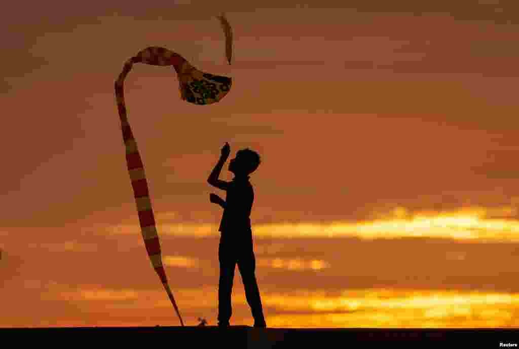 A boy is seen in silhouette as he flies a kite in Colombo, Sri Lanka.