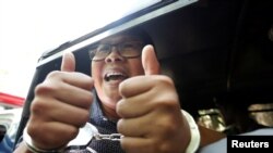 Detained Reuters journalist Wa Lone gestures to the media as he is escorted by police after a court hearing in Yangon, Myanmar, Apr. 11, 2018. 