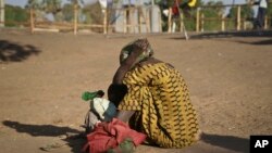 A South Sudanese refugee woman sits with her child at a refugee collection center in Palorinya, Uganda, Feb. 16, 2017.