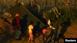 Migrantes que buscan asilo en Estados Unidos caminan cerca de una cerca con púas, en Ciudad Juarez, México. Estados Unidos y Venezuela acordaron un plan de repatriación con vuelos directos de quienes no tengan base legal para quedarse en el país norteamericano.