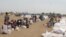 Displaced South Sudanese wait on Saturday, March 21, 2015, in Ganyiel, Unity state for sacks of food provided by the World Food Program (WFP) to be distributed. 