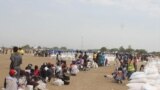 Displaced South Sudanese wait on Saturday, March 21, 2015, in Ganyiel, Unity state for sacks of food provided by the World Food Program (WFP) to be distributed. 