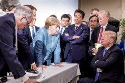 FILE - In this photo made available by the German Federal Government, German Chancellor Angela Merkel, center, speaks with President Donald Trump, seated at right, during the G7 Leaders Summit in La Malbaie, Quebec, Canada, on June 9, 2018.