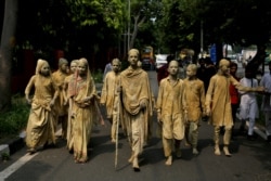 School children dressed as statues depicting Indian freedom leader Mahatma Gandhi's Dandi March cross a road to perform at a traffic intersection on the eve of Gandhi's 150th birth anniversary in New Delhi, India, Oct. 1, 2019.