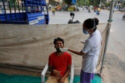 A man reacts as a health worker collects a swab sample as a precaution against COVID-19 in Ahmedabad, India, Aug. 13, 2021.