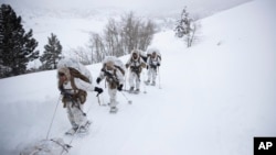 A group of U.S. Marines walk along a snow-covered trail during their advanced cold-weather training at the Marine Corps Mountain Warfare Training Center, Feb. 10, 2019, in Bridgeport, California.