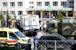 Sebuah ambulans dan truk polisi diparkir di sebuah sekolah usai penembakan di Kazan, Rusia, Selasa 11 Mei 2021. Media Rusia melaporkan bahwa beberapa orang tewas dan terluka dalam penembakan di sekolah di kota Kazan, Rusia.