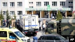 An ambulance and police trucks are parked at a school after a shooting in Kazan, Russia, May 11, 2021.