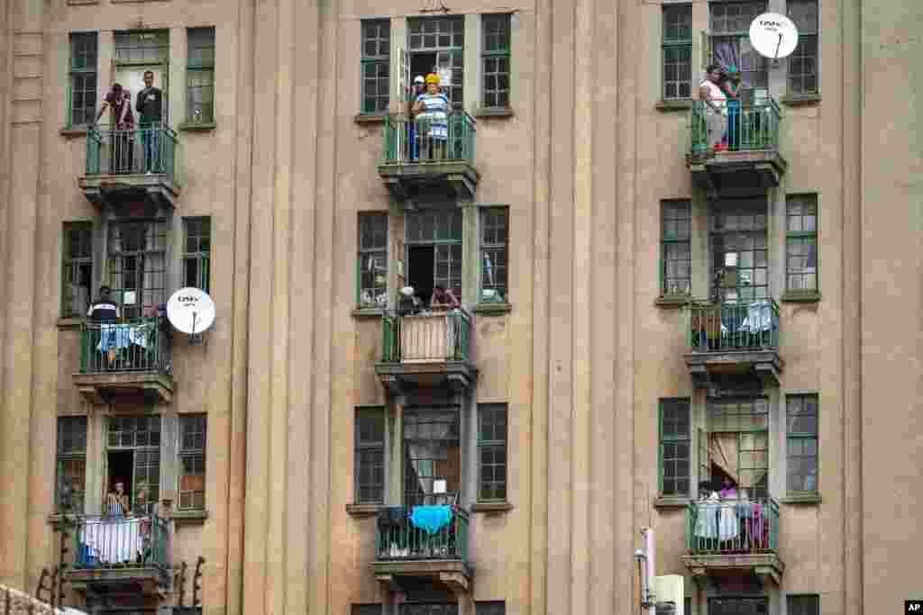 Residentes de un barrio del centro de&nbsp;Johannesburgo observan desde sus balcones que la policía sudafricana y las Fuerzas de Defensa Nacional buscan un bar local que creían que estaba abierto ilegalmente, a pesar de la cuarentena.&nbsp;