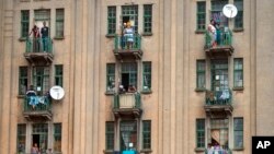 Des résidents regardent depuis leur balcon des forces de sécurité fouiller un bar qu'ils pensaient être illégalement ouvert au centre-ville de Johannesburg le 30 mars 2020.