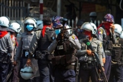 A riot police officer fires a rubber bullet toward protesters during a protest against the military coup in Yangon, Myanmar, Feb. 28, 2021.